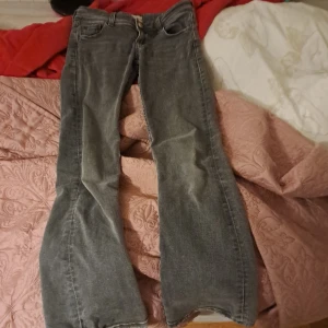 Grå jeans från Gina Tricot - Snygga grå jeans från Gina Tricot i storlek 146. De har en klassisk femficksdesign med knappar framtill och bakfickor med lock. Perfekta för en avslappnad stil.