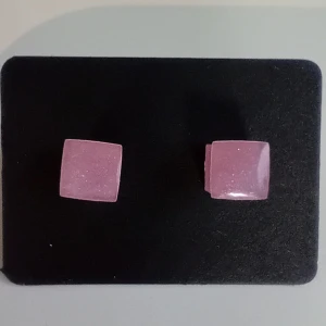 Rosa fyrkantiga örhängen - Rosa skimriga fyrkantiga örhängen gjorda i resin. Perfekta för att lägga till en färgklick till din outfit. De har en enkel och stilren design som passar till många tillfällen. Storlek på fyrkanten är ca 6mm x 6mm
