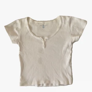 Brandy Melville topp - Topp från brandy med knappar o o detalj runt halsringen. Två fläckar på framsidan tyvärr o lite miss färgning längst upp. Storleken är ungefär s-m. Köpt för 200🤍