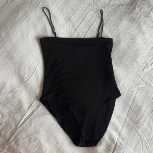 Svart bodysuit från H&M - Bodysuit från H&M med smala axelband. Perfekt för en stilren look och kan enkelt matchas med olika outfits. Strl 40