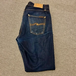 Nudie jeans - Snygga mörkblå jeans med klassiska kontrastsömmar och femficksdesign. Perfekta för en stilren look. De har en normal passform och är tillverkade i slitstarkt denim. Modellen är steady Eddie. För minsta funderingar, hör av dig👍🏻