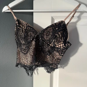 Svart/beige spetslinne - Snyggt svart spetslinne med tunna axelband och vacker spetsdetalj. 