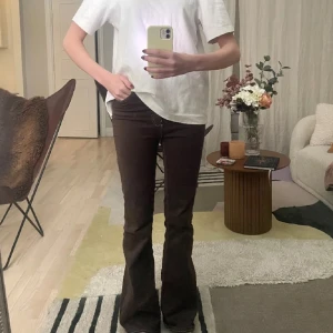 Bruna bootcut jeans - Snygga bruna bootcut jeans med vita sömmar. De har en klassisk femficksdesign och är perfekta för en avslappnad stil. Passar bra till både sneakers och klackar.