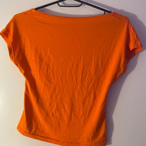 Orange topp från Shein - Säljer en snygg orange topp från Shein. Toppen har en vid halsringning, korta ärmar och en öppen rygg. Perfekt för sommardagar. Tillverkad i ett mjukt och bekvämt material.