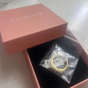 Guldfärgad ring med texten 'MOM' från Edblad - Ringen är i helt nyskick! Storlek 18,5 Inte ens uttagen från påsen. Fick den i julklapp men som ni ser på en av bilderna så har jag silver på mina smycken så måste tyvärr sälja vidare denna ringen. Nypris: 400kr. Mitt pris: 350kr.