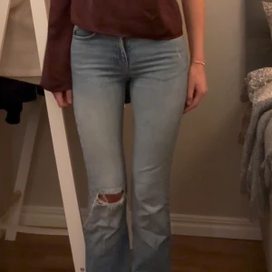 Ljusblå bootcut jeans - Snygga ljusblå bootcut jeans med slitna detaljer på knäet. Strl 34 (jag är 178cm lång)