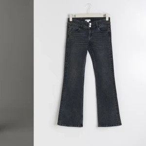 Mörkgrå bootcut jeans - Snygga mörkgrå bootcut jeans med låg midja och klassisk femficksdesign. Jeansen har en knapp och dragkedja framtill samt dekorativa sömmar. Perfekta för en stilren look. Jeansen är köpta för 349kr ifrån gina tricots barnavdelning. Jeansen är i storlek 164 men skulle säga att de är i som xs! Jeansen är i fint skick och knappt använda 