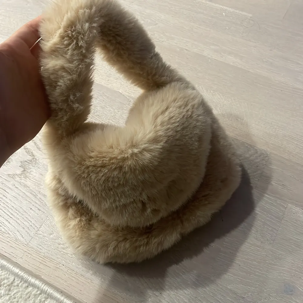 Säljer en supermjuk och fluffig beige handväska. Den är perfekt för att ge din outfit en mysig touch. Väskan har en enkel design med en magnetknapp för att hålla dina saker säkra. Den är liten och smidig, perfekt för en dag ute eller en kväll med vänner. 👜✨. Väskor.