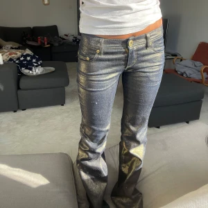 Guldglittrande Jeans!! - Sååå unika och snygga jeans i världens coolaste färg!!!😍 perfekt lowwaist och bootcut, så snygga till fest, nyårsbyxor?😮 Jag är 168cm Mått Midja: 37cm rakt över Innerbensläng: 83cm Lår: 22cm I blixt så ser de mest glittriga ut men i dagsljus guldiga!