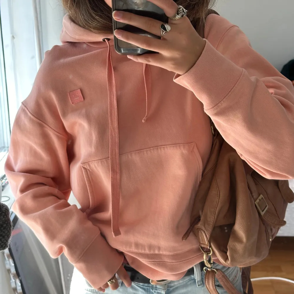 Fantastisk Acne Studios Logo hoodie i en perfekt rosa/persiko färg. Storlek M men perfekt oversized, jag har storlek S/38!  Använd några gånger men finns en blekningsdefekt (se sista bild), därav priset. Inköpt för ca 3000kr för några år sen🐙. Hoodies.