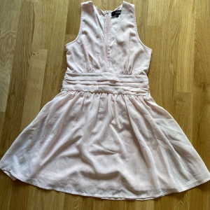 Ljusrosa klänning med rosett - Säljer en ljusrosa klänning från bubbleroom. Den är ärmlös och har en söt rosett i ryggen. Klänningen är uppsydd för att bli lite kortare då jag är 1,59. Klänningen har en normal passform och är gjord i ett mjukt och skönt material.