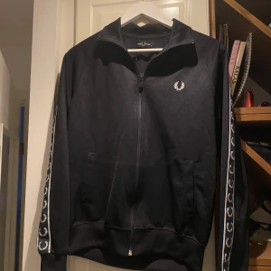 Fred Perry zip  - Säljer en Fred Perry zip-tröja i mörkblått, storlek S. Nyskick, knappt använd. Inköpt för 1700 kr, säljes nu för 1000 kr.    Kan skickas mot fraktkostnad