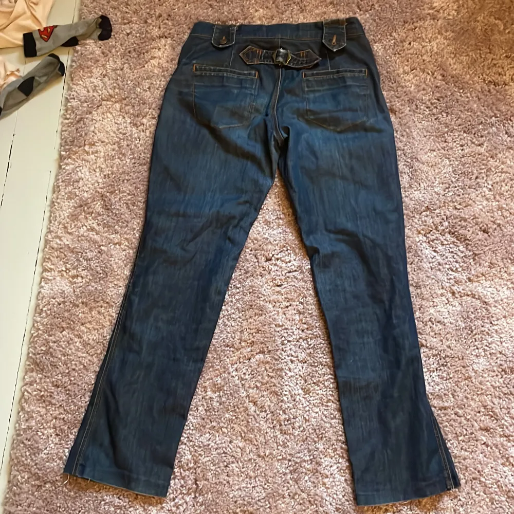 Säljer ett par snygga low/midwaist Marc Jacobs jeans med detaljer som knappar och en liten bältesdetalj bak. Älskar de men passar inte riktigt mig. Den högra knapp-detaljen där bak är lite trasig men löses lätt med en ny knapp eller säkerhetsnål.. Jeans & Byxor.