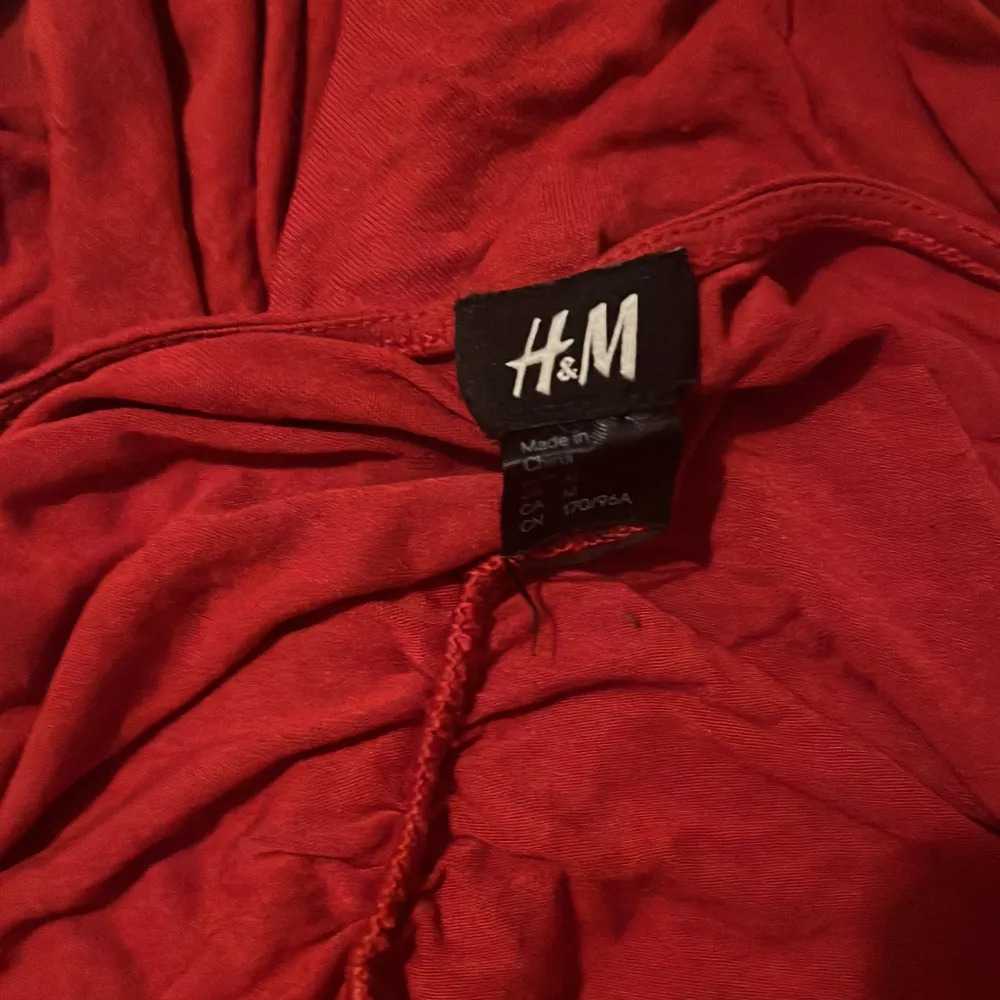 Säljer en snygg röd klänning från H&M. Den är tight och har en cool rynkad design som ger en unik look. Perfekt för fest eller en utekväll! Klänningen är ärmlös och har en v-ringad stil.. Klänningar.