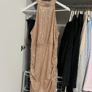 Champagnefärgad paljettklänning från Shein - Säljer en superglittrig champagnefärgad klänning från Shein. Den är ärmlös och täckt med paljetter som verkligen fångar ljuset. Perfekt för en fest eller nyårsafton! Klänningen har en tight passform och en dragkedja i ryggen för enkel påklädning.