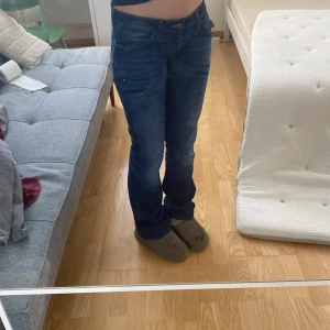 Lowwaist bootcut jeans - Blå Lågmidjade bootcut/flare jeans. Kommer från märket wrangler och strlken är  W30 L34. Tänk på att dem sitter lite för stort på mig i bilderna. Kontakta gärna för bilder, mått och prisförslag. Lite slitna längs ner (se sista bilden)🩷🩷