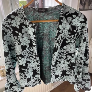 Blommig kavaj från Wönderzhul - Säljer en superfin cardigan från Wönderzhul i storlek S. Den har ett blommigt mönster i svart och mintgrön, perfekt för att liva upp vilken outfit som helst. Perfekt för vår och sommar!
