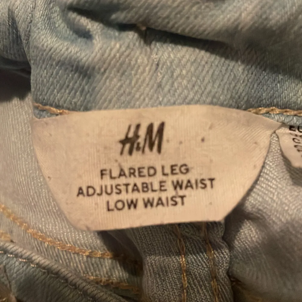 Säljer ett par ljusblå jeans från H&M. De har en flared leg och är lågmidjade med justerbar midja. Perfekta för en avslappnad stil och passar till de flesta tillfällen. Sköna och snygga!. Jeans & Byxor.