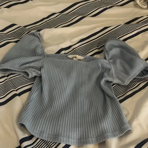 Ljusblå ribbad topp från H&M - Säljer en superfin ljusblå ribbad topp från H&M. Den har puffiga kortärmar och en söt knytning i ryggen. Perfekt för vår och sommar! 💙
