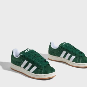 Gröna Adidas Campus 00 - Snygga gröna Adidas Campus 00 sneakers i mocka med de klassiska vita ränderna på sidan. Skorna har en bekväm passform och är perfekta för både vardag och fritid. De har en vit sula och snörning framtill. Köpta på JD sports i Spanien!! Knappt använda, därav priset! Priset går att diskutera vid snabb affär! Nypris: 1349kr