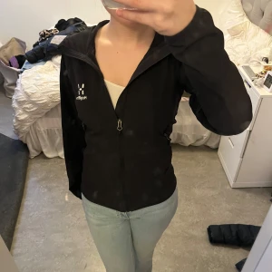 Svart jacka från Haglöfs - Säljer en svart jacka från Haglöfs i storlek XS. Den har en dragkedja framtill och två praktiska fickor med dragkedjor. Perfekt för höst och vår, med en stilren design och långärmad passform. Jackan är i mycket bra skick och redo för nya äventyr!