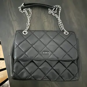 Säljer min otroligt fina svarta 100% läderväska med silver kedja från DKNY.  Väskan köptes i USA inne i DKNY butik. Fint skick, försiktigt använt Dustbag tillkommer.