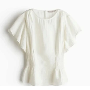 Vit blus med volangdetaljer - Säljer en superfin vit blus med korta ärmar och volangdetaljer och ribbning i midjan❣️