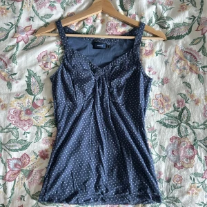 Blå prickig topp  - Säljer en söt blå linnetopp från Mexx med vita prickar. Toppen har en smickrande v-ringning och rynkdetaljer framtill. 