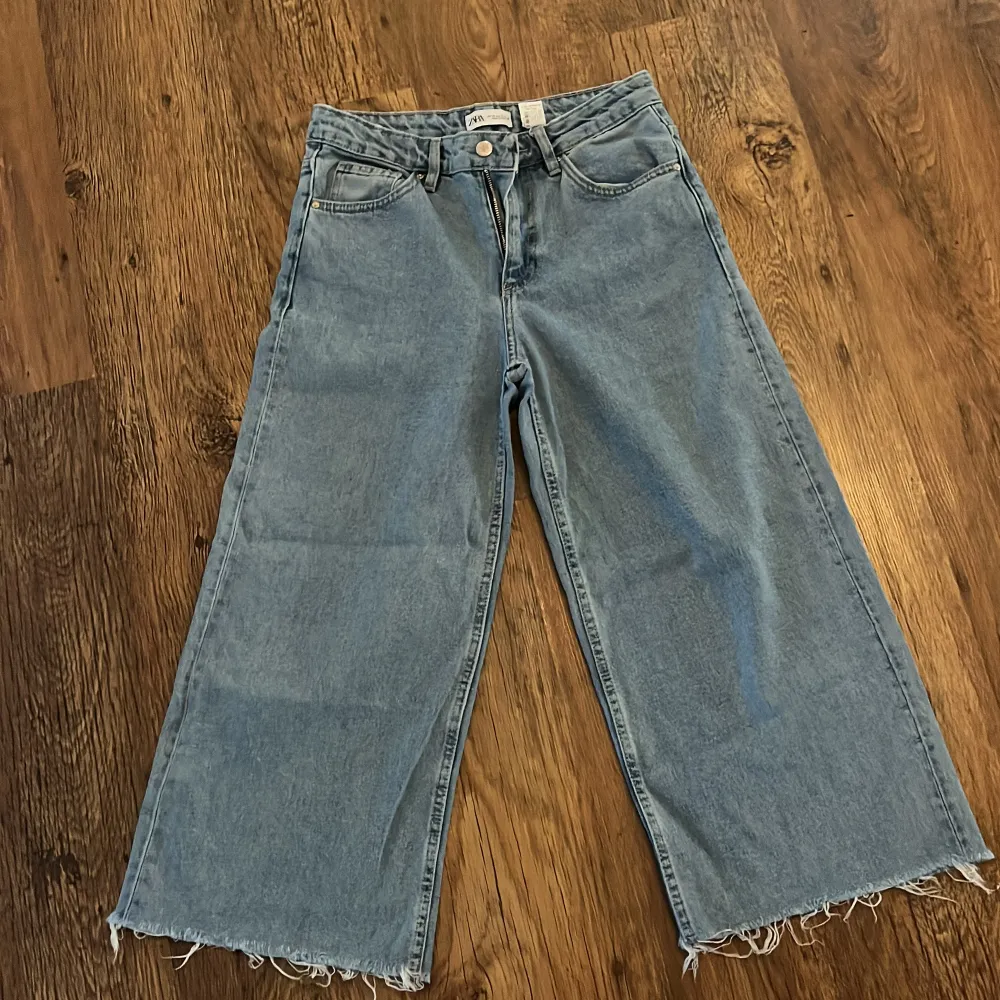 Säljer ett par ljusa jeans i loose fit med fransig kant nertill. De är högmidjade och har en avslappnad, bred passform som är perfekt för en casual look. Jeansen har klassiska fem fickor. Perfekta för både vår och sommar!. Jeans & Byxor.