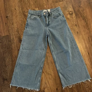 Ljusa jeans med fransig kant - Säljer ett par ljusa jeans i loose fit med fransig kant nertill. De är högmidjade och har en avslappnad, bred passform som är perfekt för en casual look. Jeansen har klassiska fem fickor. Perfekta för både vår och sommar!