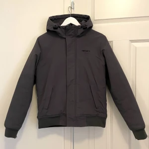 Carhartt jacka - En tuff Carhartt jacka som både är snygg och varm. Lite slitningar längst ut på ärmen annars inget fel på den. Nypris 2600kr.