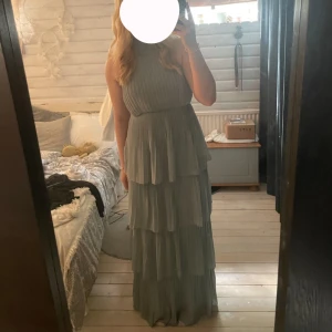 Salvia grön långklänning med volanger - Säljer min fina balklänning ifrån 9an. Endast använt en gång , den har inga defekter utan precis som ny. Perfekt inför festligheter och bal. Kontakta mig för fler bilder💗