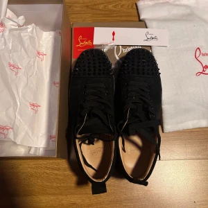Svarta Louboutin skor strl:40-41 - Säljer nu ett par svarta sneakers från christian louboutin i mycket bra skick. Skorna har en ikonisk röd sula och är gjorde i mocka. Perfekta för båda vardag och fest. Det tillkommer dust bag och box när man köper skorna. En spik fattas på skon men det tillkommer extra spikar så man kan fixa till det själv men det är inget man märker så mycket. Pris kan diskuteras