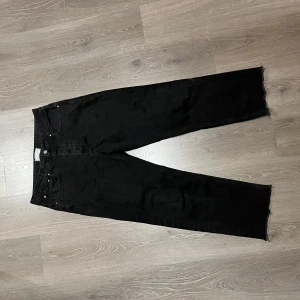 Svarta jeans från ASOS DESIGN - Säljer ett par svarta jeans från ASOS DESIGN i bra skick. De har en straight passform och är gjorda av bomull. Perfekta för höst och vinter med en stilren look. De har en rå kant vid bensluten för en trendig touch.