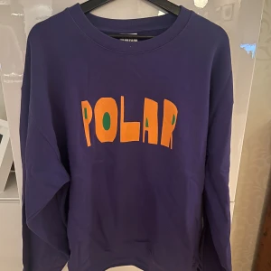 Mörkblå sweatshirt från Polar - Säljer en snygg mörkblå sweatshirt från Polar med färgglad text på framsidan. Tröjan är i mycket bra skick och perfekt för både vardag och chill. Den har långa ärmar och en bekväm passform. Perfekt för höst och vinter!