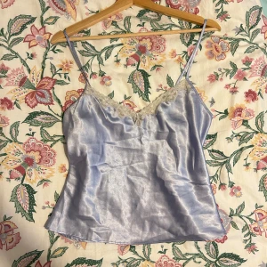 Ljusblå satinlinne med spetsdetaljer - Säljer ett supergulligt ljusblått satinlinne med smala axelband och spetsdetaljer vid halsringningen. Har några mindre slitage/tecken på användning. Ber om ursäkt att den är rynkig på bilden 🫧✨