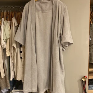 Grå frottérock - Mysig grå frottérock perfekt för att slappa hemma. Den har en avslappnad passform med trekvartsärmar och är gjord i mjukt frottématerial. Perfekt för kyliga morgnar eller efter duschen. Det finns även band till morgonrocken. Märket är okänt men storleken passar S-M