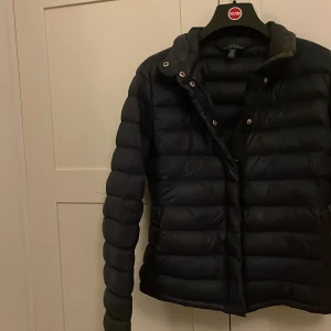 Mörkblå dunjacka från Ralph Lauren - Säljer en snygg mörkblå dunjacka från Ralph Lauren i mycket bra skick. Jackan har långa ärmar och stängs med både dragkedja och knappar. Perfekt för kyliga höst- och vinterdagar. Den är quiltad och har en klassisk stil som passar till det mesta. 🧥Är i barnmodell så är 16år