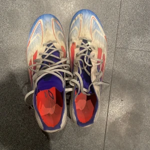 Adidas F50 Elite - Säljer dessa tvär feta Adidas F50 i vitt med blå och röda detaljer. Skorna är i bra skick , använda i ungefär 1 månad. Skorna är väldigt lätta vilket gör dig snabbare på planen! Nypris 3000. Priset är inte hugget i sten. Vid minsta lilla fundering hör av dig till mig!