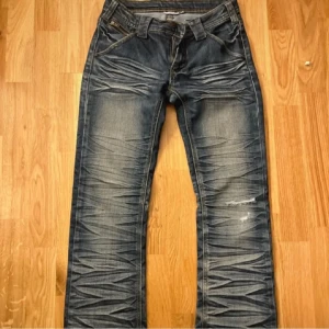 Blå jeans med slitningar - Snygga blå jeans med coola slitningar och en lätt tvättad look. De har en klassisk femficksdesign och bootcut ben. Perfekta för en avslappnad stil.