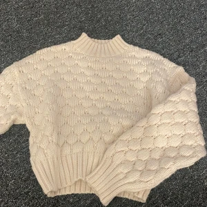 Vit stickad tröja - Mysig vit stickad tröja med ett unikt mönster och ribbade kanter. Perfekt för kyliga dagar och ger en stilren look. Passar bra till både jeans och kjol.