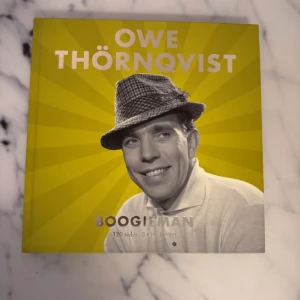 Owe Thörnqvist - Boogieman - En bok med titeln 'Boogieman' av Owe Thörnqvist. Innehåller 120 sidor och en samling av hans studiomaterial. Boken har ett gult omslag med en bild av Owe Thörnqvist i hatt. Inkluderar även en DVD med konsert och dokumentär samt bonusmaterial.