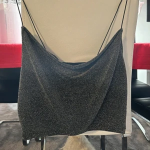 Linne - Snygg svart glittrig rätt så kort linnetopp från H&M med tunna axelband. Perfekt för en kväll ute eller festliga tillfällen. Toppen har en elegant och stilren design. Storlek M och inga defekter på användning!🍸🥂