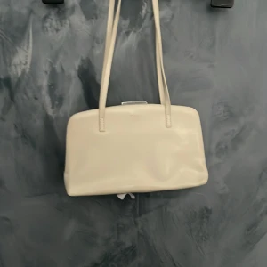 Beige axelväska från ENJOYI - Snygg beige axelväska från ENJOYI med stilren design. Väskan har en praktisk dragkedja på insidan för säker förvaring. Perfekt för att bära med sig det nödvändigaste med stil.