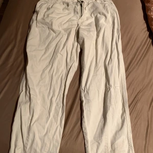 Beige byxor med dragkedja - Säljer ett par bekväma beige byxor med dragkedja och elastisk midja. Perfekta för en avslappnad stil. De har en enkel design som gör dem lätta att matcha med olika outfits.