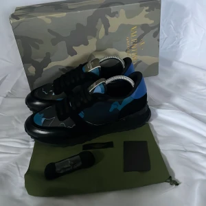 Valentino Rockrunners - Snygga Valentino Garavani sneakers med ett unikt camouflage-mönster i blått och svart. Skorna har en robust sula och klassisk snörning. Perfekta för att ge din outfit en stilfull touch.