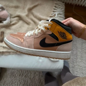 Nike Air Jordans i - Snygga Nike Air Jordans i beige/rosa och svart med gula detaljer. Skorna har en klassisk snörning och en bekväm passform. Perfekta för dig som vill ha en stilren look med en touch av färg. Använda men inget slitage mer än att dem behövs torkas av. 