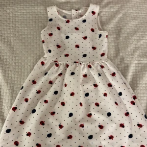 Vit klänning med nyckelpigemönster från H&M - Charmig vit klänning från H&M med ett lekfullt nyckelpigemönster i rött och svart. Klänningen är perfekt för sommaren så passa på att köpa den nu då den är billigare! Storlek 134-140💕den är helt oanvänd också🌸