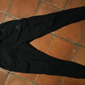 Svarta mjukisbyxor från Nike - Säljer ett par svarta mjukisbyxor från Nike med elastisk midja och snörning. Byxorna har en diskret Air Max-logga och är perfekta för en avslappnad stil.