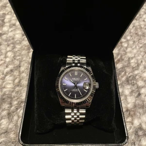 Stilren Seikomodifierad klocka  - Just nu säljs en elegant Seiko-modifierad automatisk klocka med en mörkblå stilren urtavla som sticker ut från vardagen. Denna klocka har en unik design med noggrant utvalda detaljer som ger den en modern känsla. Såsom en räfflad bezel som ger en trendig look. Länkar ingår, vilket gör att du kan justera storleken för en perfekt passform. 